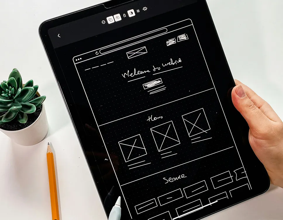Custom WordPress Design service featured image_Human hand holding a tablet with a digitally drawn user interface wireframe